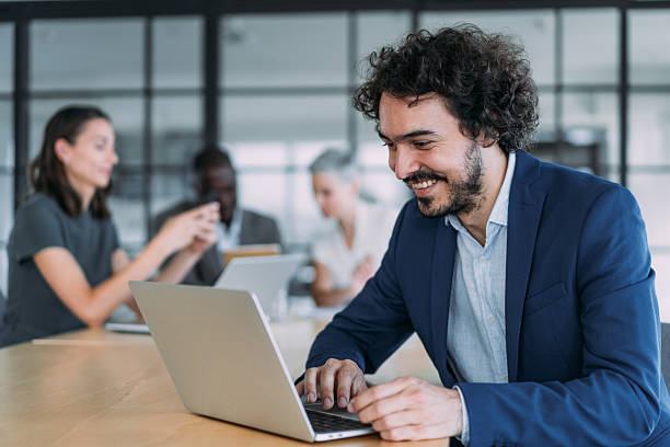 Shot of a handsome businessman using laptop during meeting in office board room. Group of business persons in business meeting. Group of entrepreneurs on meeting in board room. Corporate business team on meeting in the office.